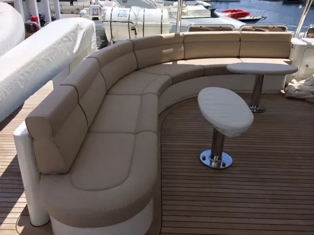 Teak güverte üzerinde bej kumaşla kaplanmış, kavisli flybridge oturma grubu ve minderleri