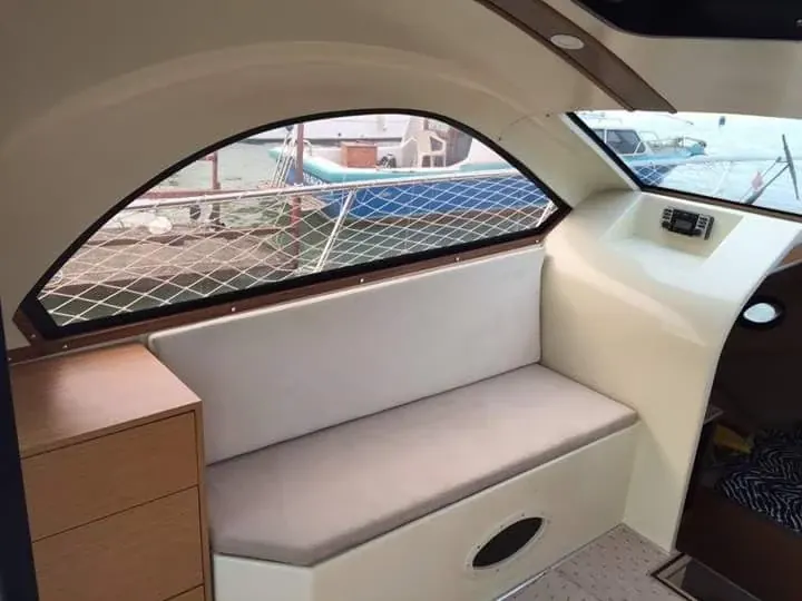 Kabin penceresi altında açık gri minderli oturma yeri